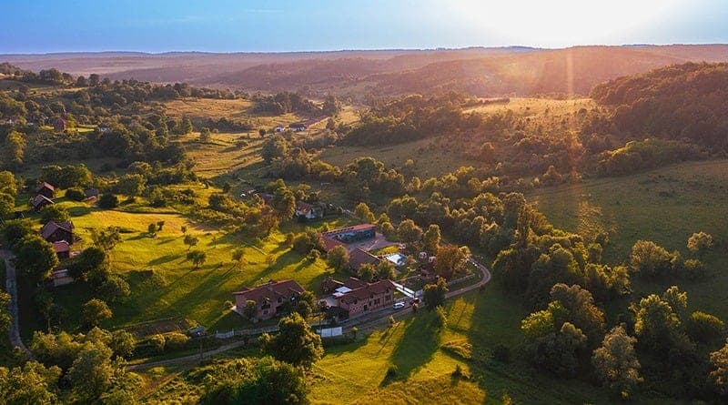 Valea de la Labașinț văzută de sus, la apus: case răsfirate pe pajiști și dealuri împădurite până la orizont.